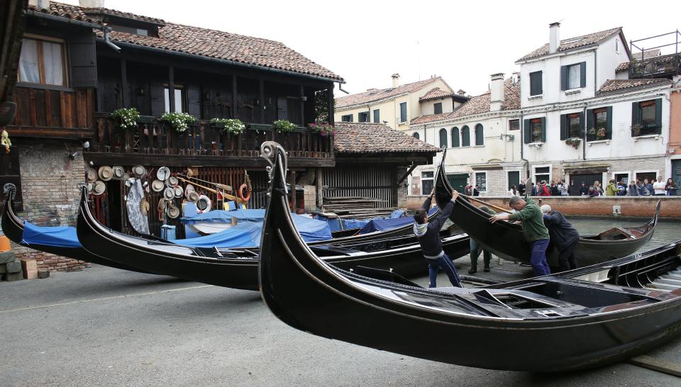 Workers carry a gondola for maintenance at the San Trovaso boatyard, also known as a