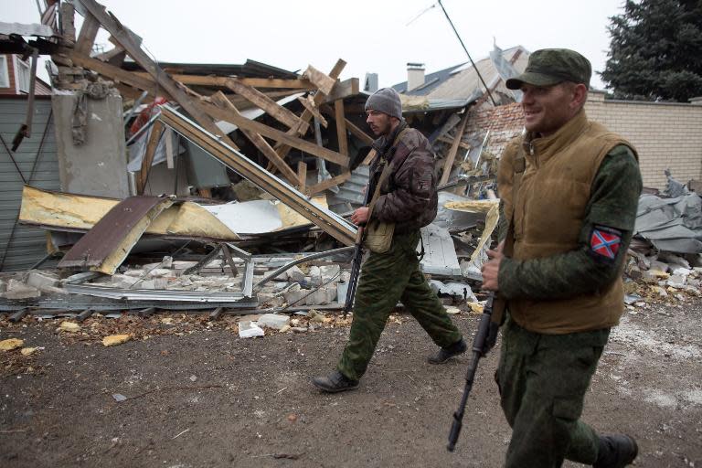 Pro-Russian gunmen walk past destroyed houses in the North West suburb of Donetsk, eastern Ukraine, on November 13, 2014
