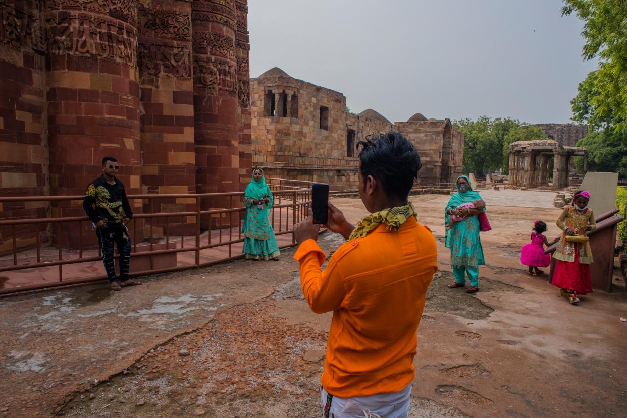 Tourists take their pictures in front the United Nations Educational, Scientific and Cultural Organisation (UNESCO) World Heritage Site of Qutub Minar complex on July 6, 2020, in New Delhi, India. Barring the iconic Taj Mahal, the Archeological Survey of India (ASI) Monday opened for the public the historical monuments which had remained closed for several months after the Indian government imposed a nationwide lockdown on March 25 to curb the spread of coronavirus.