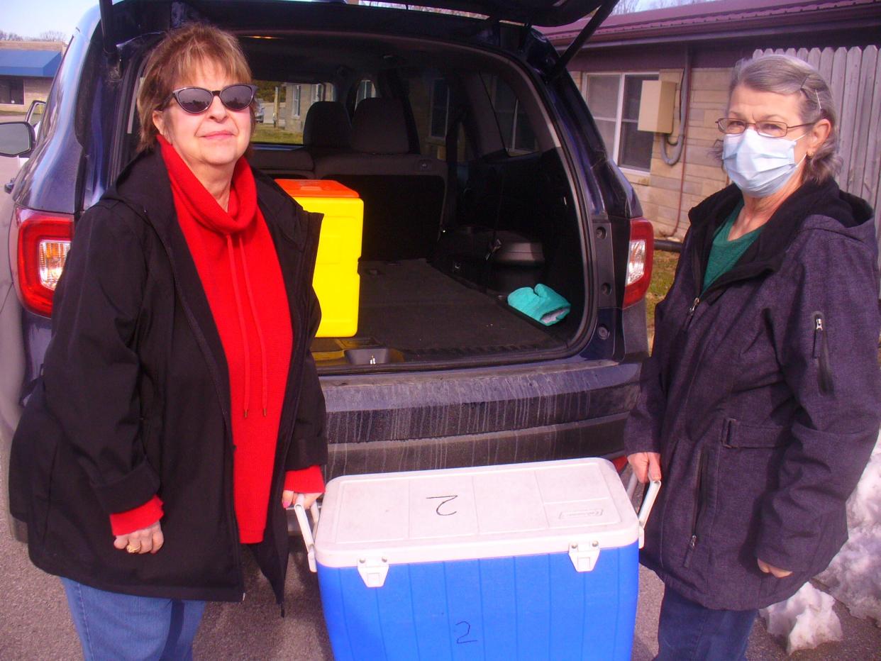 Michelle Liptak (left) and Pat Winter hoist their box of food from Meals on Wheels headquarters on North Walnut Street into Liptak's vehicle. The food is prepared each morning in kitchens at IU Health Bloomington Hospital and at Meadowood Retirement Community.