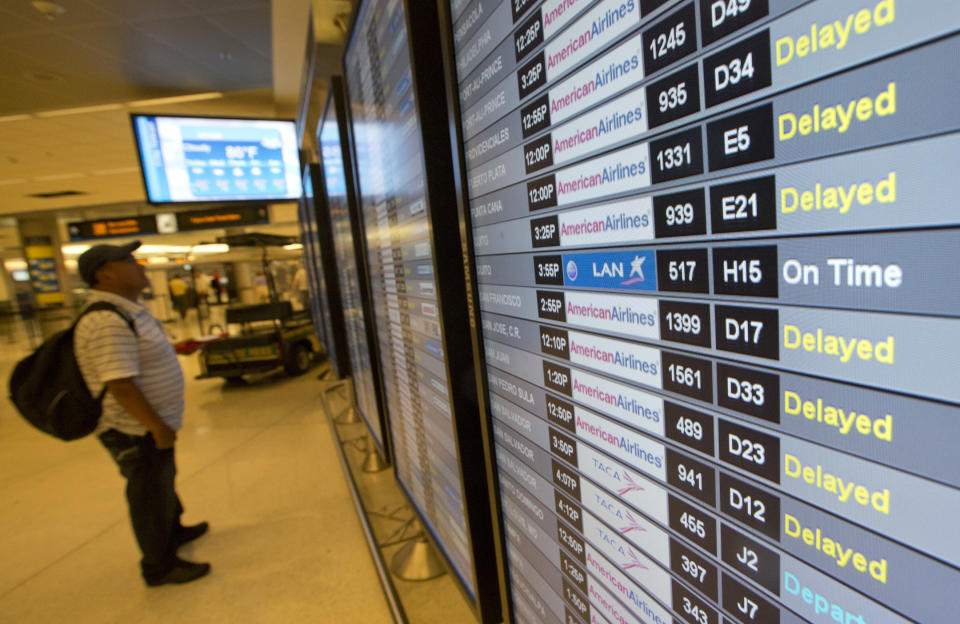 An unidentified passenger checks the flight information board at the Miami International Airport, Tuesday, April 16, 2013. American Airlines says it has fixed an outage in its main reservations system that is disrupting travel for thousands of passengers whose flights have been delayed or canceled. But the airline expects to see flight delays and cancellations throughout the rest of the day. (AP Photo/J Pat Carter)
