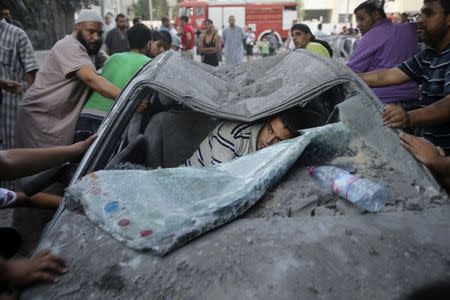 A Palestinian inspects the wreckage of a car, which witnesses said was hit by a nearby Israeli air strike that killed three senior Hamas military commanders, in Rafah in the southern Gaza Strip August 21, 2014. REUTERS/Ibraheem Abu Mustafa