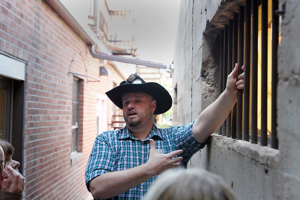 Clint Burkholder, lead tour guide for Fort Collins Tours, points to an old jail cell during a recent ghost tour in Old Town on Aug. 27. The story of Eva Howe's murder and James Howe's lynching is a central story on the company's weekend ghost tours.