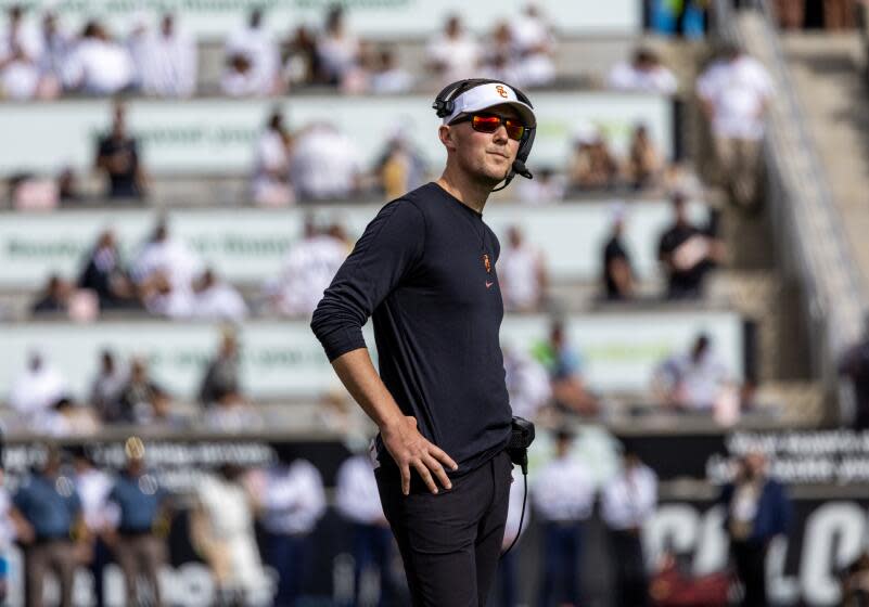 USC coach Lincoln Riley wears sunglasses, rests his hands on hips and looks at Colorado scoreboard during a tight game