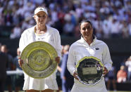 Kazakhstan's Elena Rybakina, left, holds the trophy after beating Tunisia's Ons Jabeur to win the final of the women’s singles on day thirteen of the Wimbledon tennis championships in London, Saturday, July 9, 2022. (Zac Goodwin/PA via AP)