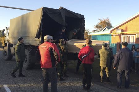 Russian servicemen unload a coffin containing the body of Vadim Kostenko, one of the Russian air force's support staff in Syria, from a truck near his family's house in the village of Grechnaya Balka, north-west of Krasnodar, Russia, October 27, 2015. The body of the first Russian serviceman confirmed dead in four weeks of air strikes in Syria was delivered on Tuesday to his parents, who said they were not convinced by the military's account that their 19-year-old son had hanged himself. In an interview with Reuters at their home in southern Russia before they received the body of their son Vadim, Alexander and Svetlana Kostenko said their son had sounded cheerful over the phone as recently as Saturday, the day he died while working at an air base on the Syrian coast. REUTERS/Maria Tsvetkova