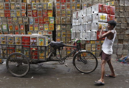 A man loads empty containers of edible oil onto a tricycle at a roadside in Kolkata, India, August 27, 2015. REUTERS/Rupak De Chowdhuri