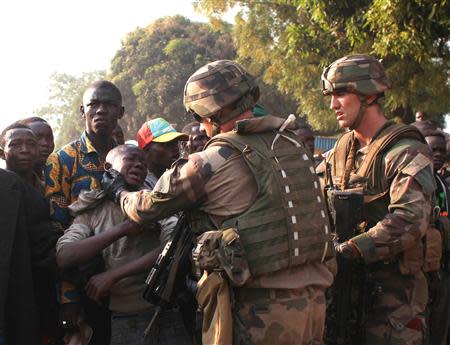 French military personnel try to control supporters who are asking them to disarm fighting gangs, near the airport in Bangui December 23, 2013. REUTERS/Andreea Campeanu