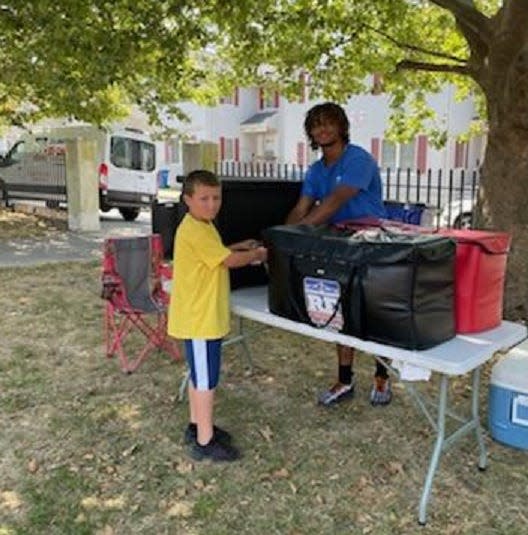 Former Durfee running back and Suffield Academy football player Jason Hall passes out lunch to children at Griffin Park in Fall River.