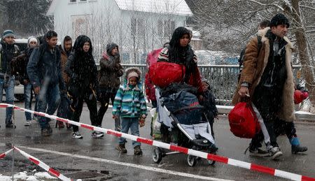 Migrants stay in queue during heavy snowfall before passing Austrian-German border in Wegscheid in Austria, near Passau November 22, 2015. REUTERS/Michael Dalder