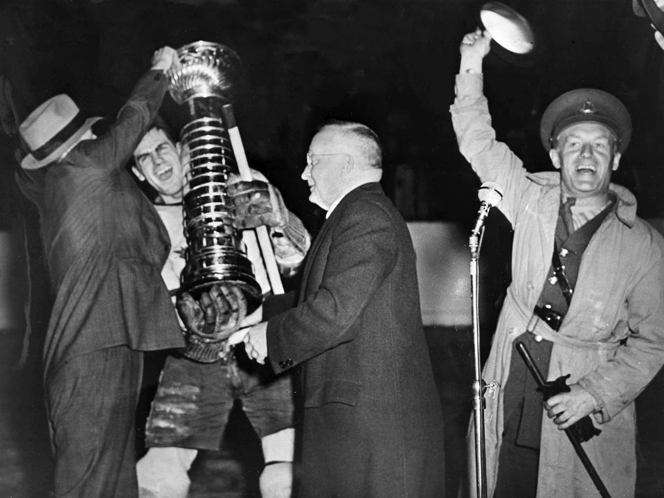 FILE - NHL President Frank Calder, center, presents the Stanley Cup to Toronto captain Syl Apps in Toronto, April 18, 1942. Maj. Conn Smythe, right, home on leave from his regiment, cheers the presentation. Toronto became the only team in the major North American sports leagues to complete a comeback from 3-0 down, to the Detroit Red Wings, to win a championship series. (AP Photo, File)