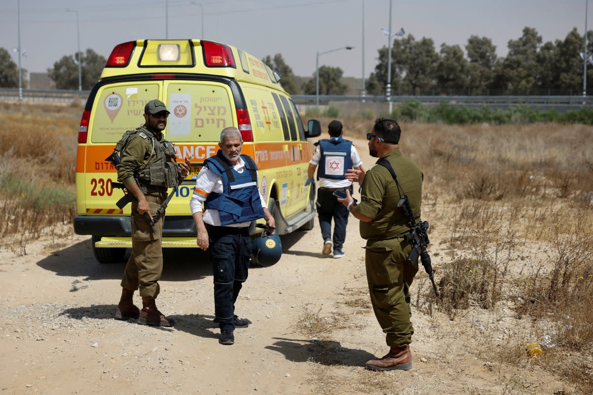 Israeli soldiers and medics walk near an ambulance after Hamas claimed responsibility for an attack on Kerem Shalom crossing (REUTERS)