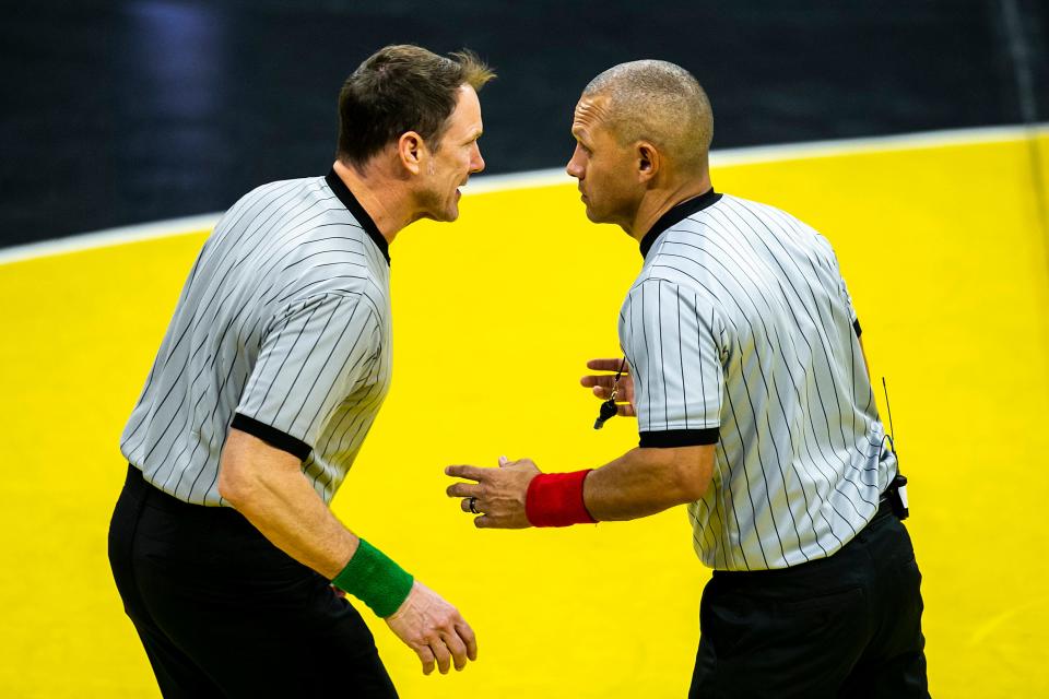 Referees Jay Cox, left, and Angel Rivera discuss a call during a NCAA college men's wrestling dual between Iowa and Oklahoma State, Sunday, Feb. 19, 2023, at Carver-Hawkeye Arena in Iowa City, Iowa.