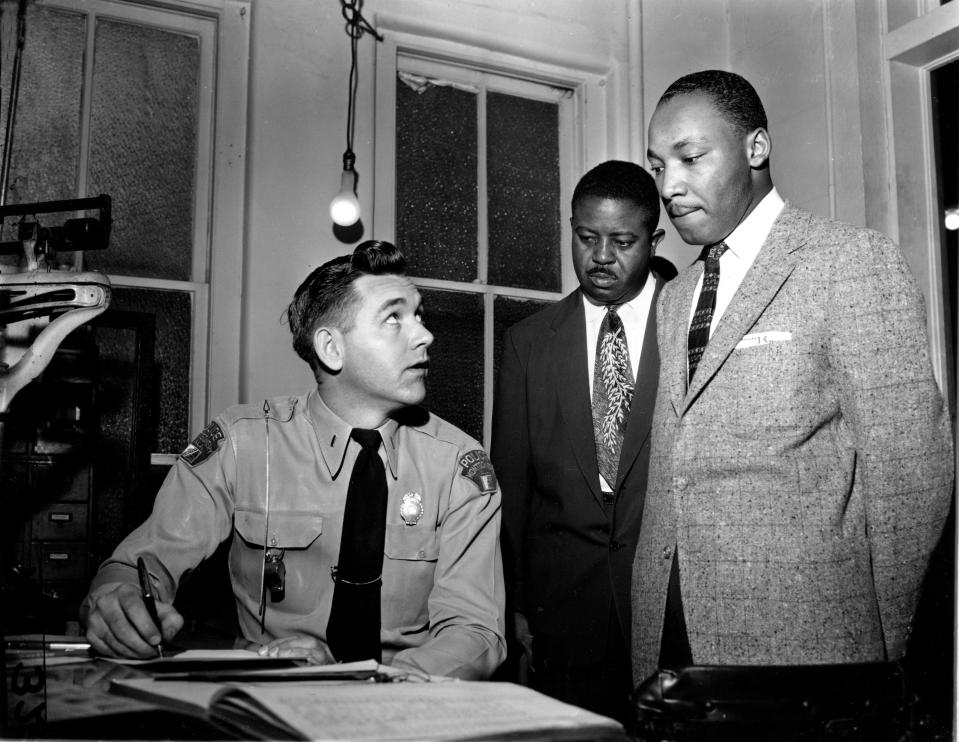 The Rev. Martin Luther King Jr., right, accompanied by Rev. Ralph D. Abernathy, center, is booked by city police Lt. D.H. Lackey in Montgomery, Ala., on Feb. 23, 1956.  The civil rights leaders are arrested on indictments turned by the Grand Jury in the bus boycott.
