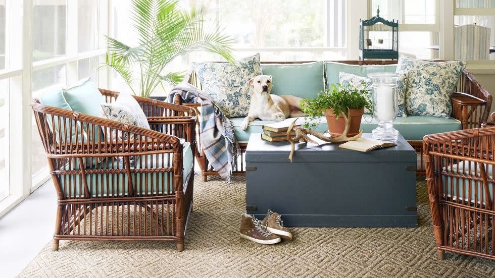 a screened porch with a fan with rattan furniture