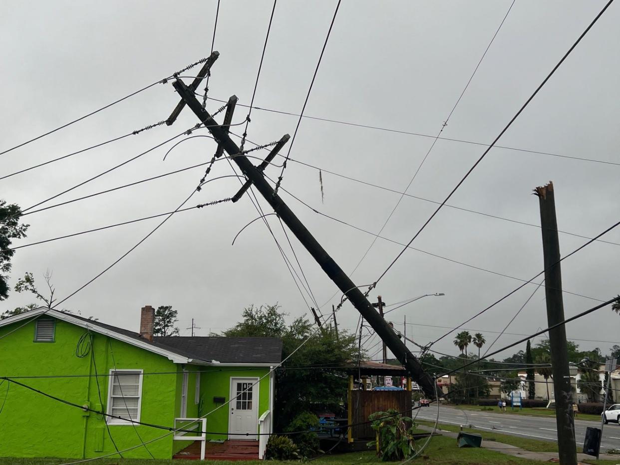 An uprooted utility pole dangles above a sidewalk at Pensacola Street and Lipona Drive, Friday May 10, 2024