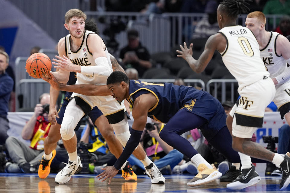 Wake Forest forward Andrew Carr, left, looks to pass to Wake Forest guard Kevin Miller as he is guarded by Notre Dame forward Kebba Njie, bottom, during the first half of the Atlantic Coast Conference second round NCAA college basketball tournament game Wednesday, March 13, 2024, in Washington. (AP Photo/Susan Walsh)