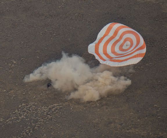 The capsule landing with its parachute beside it.