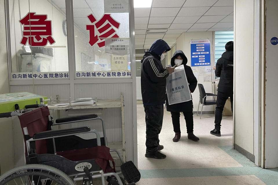 Visitors to the Baigou New Area Aerospace Hospital stand near the words "Emergency Clinic" in Baigou, in northern China's Hebei province on Thursday, Dec. 22, 2022. As China grapples with its first-ever wave of COVID mass infections, emergency wards in the towns and cities to Beijing's southwest are overwhelmed. Intensive care units are turning away ambulances, residents are driving sick relatives from hospital to hospital, and patients are lying on floors for a lack of space. (AP Photo)