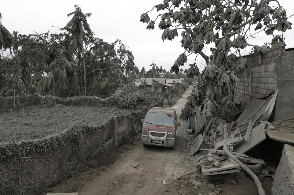 A vehicle navigates the volcanic ash covered village in Talisay, Batangas province, southern Philippines on Wednesday Jan. 15, 2020. Taal volcano is spewing lava into the sky and trembled constantly, possibly portending a bigger and more dangerous eruption, as tens of thousands of people fled villages darkened and blanketed by heavy ash. (AP Photo/Aaron Favila)