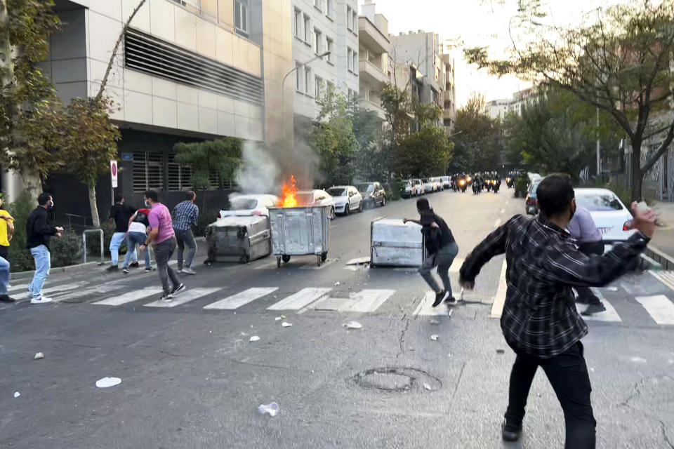 Protesters in Tehran throw stones at police during demonstrations Tuesday over the death of a young woman who had been detained for violating the country's conservative dress code. (AP)