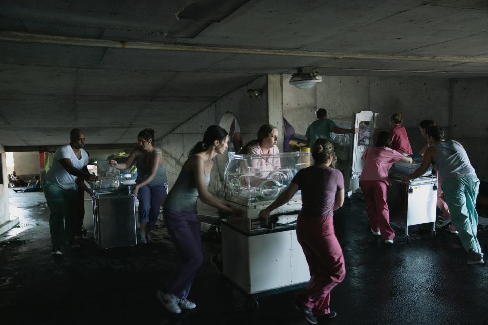 Doctors and nurses rush infants from the neonatal intensive care unit to a helipad to be evacuated from a hospital surrounded by the aftermath of Hurricane Katrina in a scene from “Five Days at Memorial.” The eight-episode series, co-written and executive-produced by John Ridley, premieres on Apple TV+ Aug. 12.