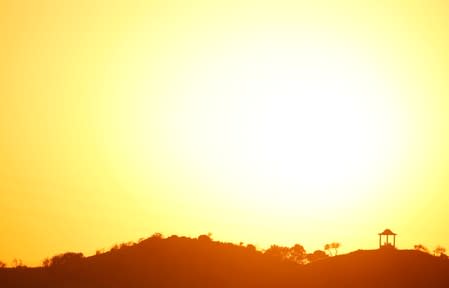 People are silhouetted against the setting sun at "El Mirador de la Alemana" in Malaga