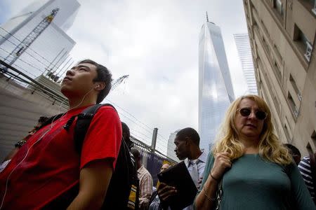 People pause near the 9/11 Memorial site during memorial observances on the 13th anniversary of the 9/11 attacks at the site of the World Trade Center in New York, September 11 2014. REUTERS/Brendan McDermid