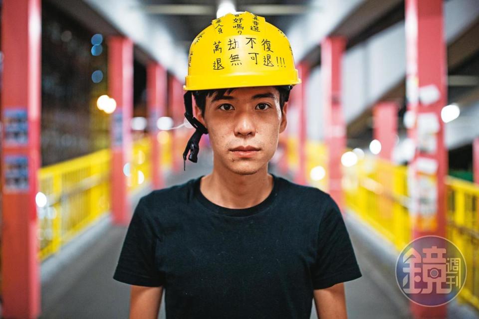 2019年反修例運動期間，岑敖暉接受本刊專訪後站在一處地鐵站拍照，頭上安全帽寫著抗爭標語。