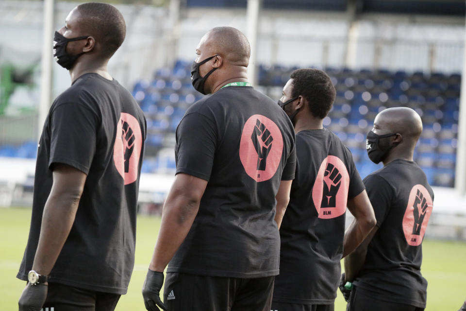 Members of all the MLS soccer teams march around the stadium before a match Wednesday, July 8, 2020, in Kissimmee, Fla., while wearing shirts and masks with messages about race. (AP Photo/John Raoux)