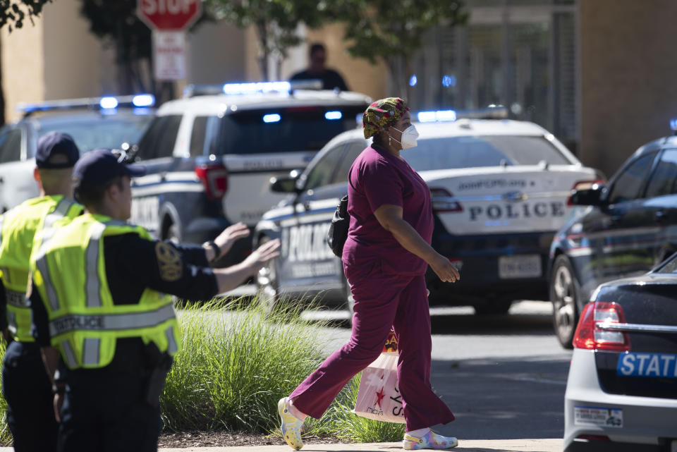 A woman walks away from the Tysons Corner Center mall following a shooting inside the shopping center, in Tysons Corner, Va., Saturday, June 18, 2022. (AP Photo/Cliff Owen)