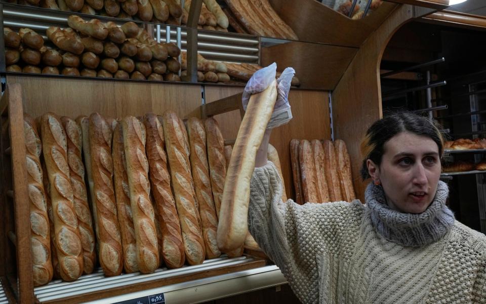 Mylene Poirier talks to a customer as she takes a baguette at the bakery - Michel Euler