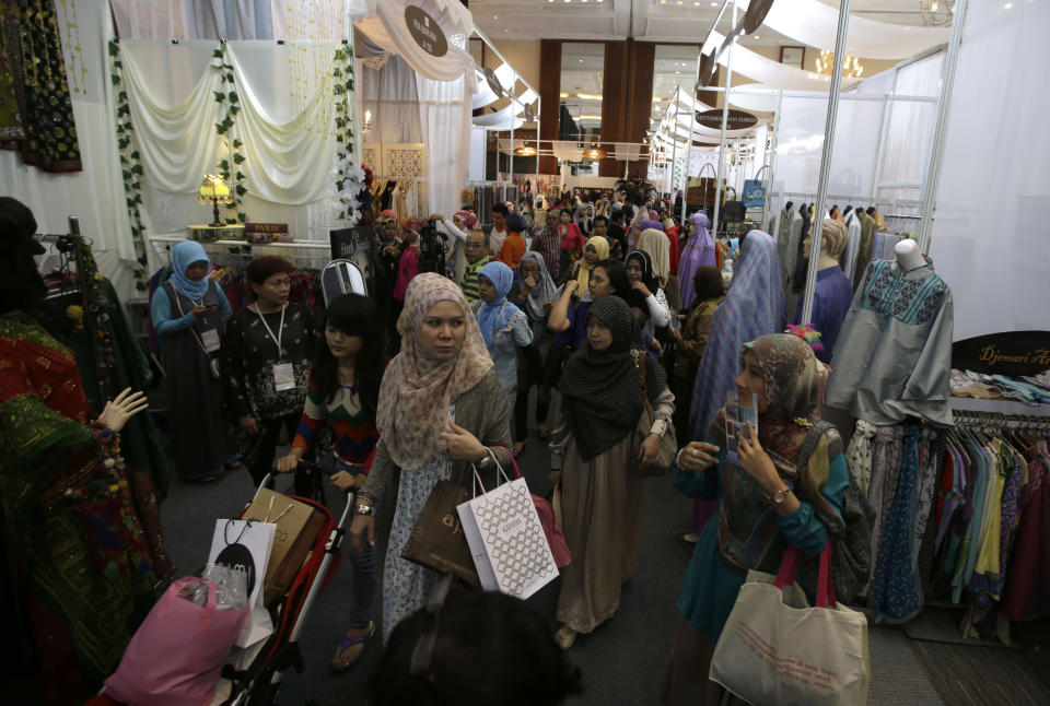 In this Thursday, May 30, 2013 photo, Indonesian Muslim women browse exhibitors' booths during Islamic Fashion Fair in Jakarta, Indonesia. Indonesia is the world's most populous Muslim country, but most people follow a moderate form of the religion. Many women wear bright and creative headscarves along with brand-name jeans and long-sleeved fitted shirts. (AP Photo/Dita Alangkara)