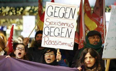 Women shout slogans and hold up a placard that reads "Against Sexism - Against Racism" as they march through the main railway station of Cologne, Germany, January 5, 2016. REUTERS/Wolfgang Rattay