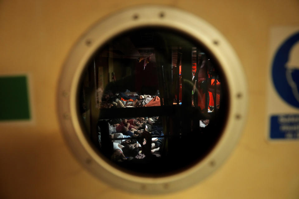 A view of migrants through a window as they sleep on the deck of the Spanish NGO Open Arms lifeguard ship after they were rescued from open waters during an operation in the international waters zone, on the Mediterranean sea, early Tuesday, Sept. 20, 2022. Around four hundred migrants from Egypt, Syria, Pakistan Bangladesh, Eritrea, Sudan, Ethiopia, Somalia, were rescued by NGO Open Arms crew members. (AP Photo/Petros Karadjias)