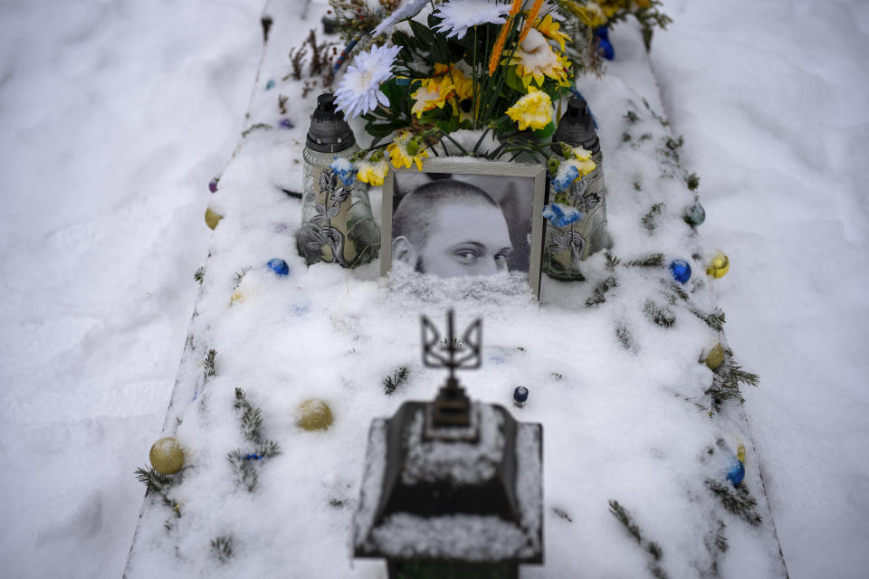 A portrait of Sgt. Oleksandrovych Sixoy, 30, partially-covered by snow, sits on his grave at a cemetery in Lviv, Ukraine Tuesday, Feb. 7, 2023. He was killed on April 13, 2022. (AP Photo/Emilio Morenatti)