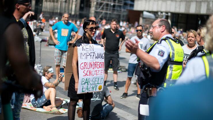 Ein Polizist diskutiert mit einer Demonstrantin auf dem Roncalliplatz. Foto: dpa