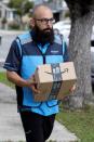 Danny Gonzalez walks with a package when he delivers for Amazon during the outbreak of the coronavirus disease