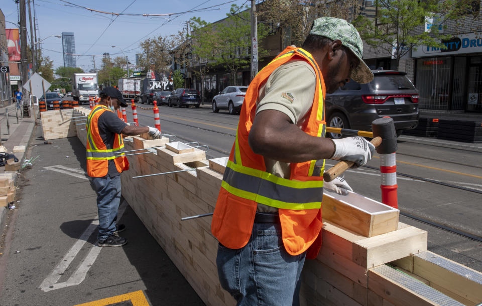 Workers assemble curb lane patio protection for the CaféTO restaurant program, in Toronto, Friday, May 21, 2021. THE CANADIAN PRESS/Frank Gunn
