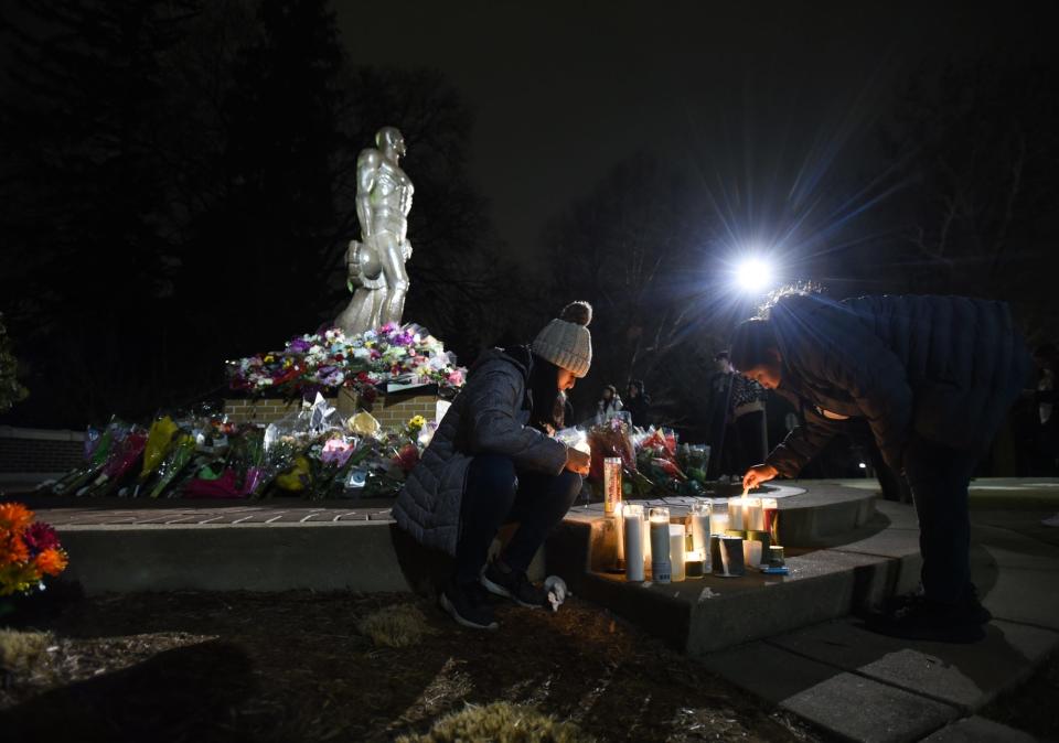 MSU sophomore Nancy Aragon, left, and cousin Sara Aragon, an MSU alumnus light candles near the Sparty statue after thousands of Michigan State University community members gathered at the Rock on campus on Wednesday, Feb. 15, 2023, to honor the lives of three students killed during a shooting rampage on campus on Monday.