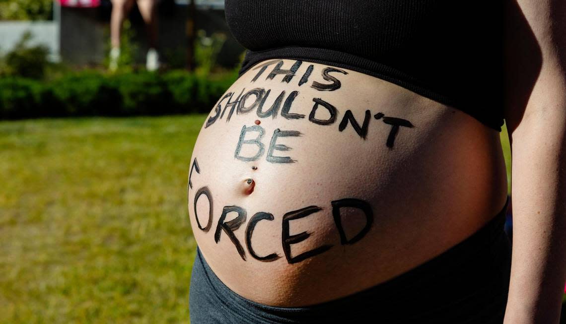 Megan Ewins shows off a message on her exposed pregnant belly that reads, “This shouldn’t be forced.” Ewins was one of many who attended a protest against banning abortion on Saturday at Cherie Buckner Webb Park in Boise.