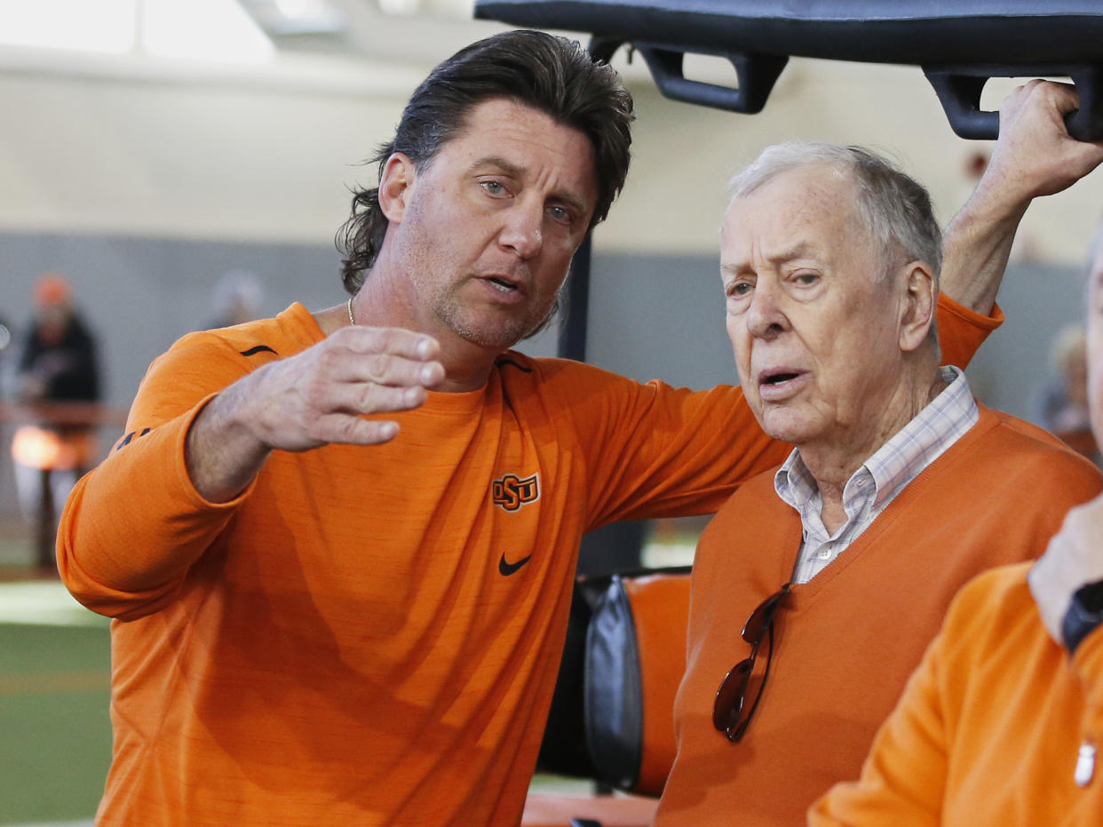Oklahoma State head coach Mike Gundy, left, explains a drill to T. Boone Pickens, right, during an NCAA college football Pro Day in Stillwater, Okla., Thursday, March 15, 2018. (AP Photo/Sue Ogrocki)