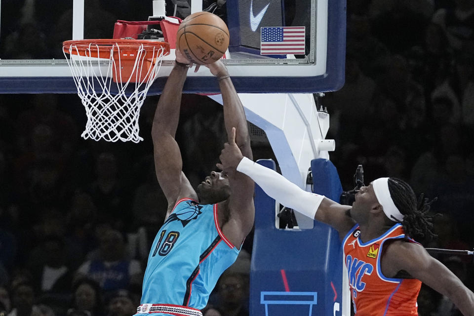 Phoenix Suns center Bismack Biyombo (18) is fouled by Oklahoma City Thunder guard Luguentz Dort (5) in the first half of an NBA basketball game Sunday, March 19, 2023, in Oklahoma City. (AP Photo/Sue Ogrocki)
