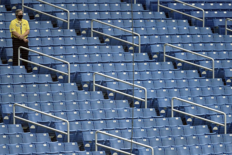 A security guards stands watch over empty seats during the fourth inning of a baseball game between the Tampa Bay Rays and the Toronto Blue Jays Sunday, July 26, 2020, in St. Petersburg, Fla. There are no fans allowed in the stadium to help stop the spread of the corona virus. (AP Photo/Chris O'Meara)