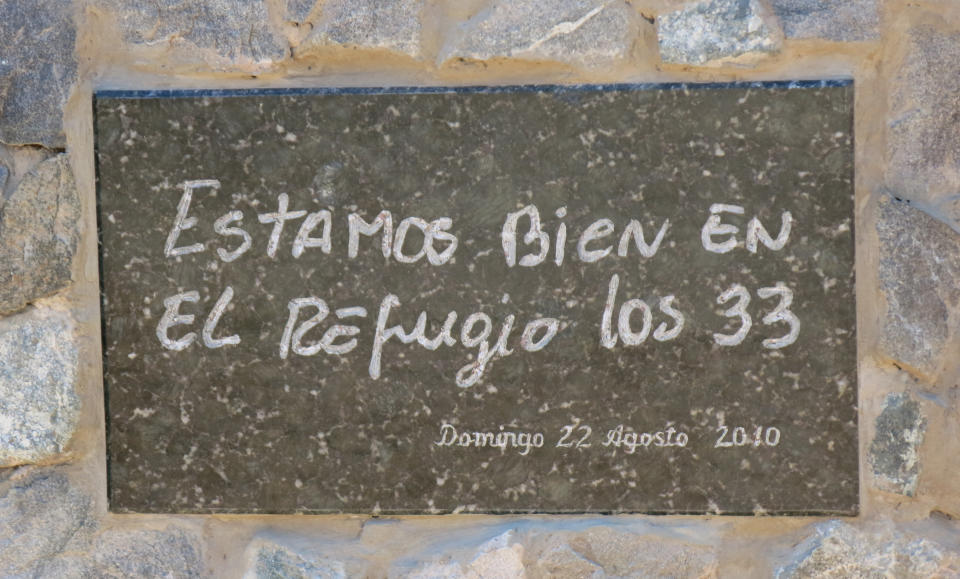 In this Feb. 12, 2014 photo, a plaque shows a copy of the hand written message by a trapped miner that reads in Spanish "We are okay all 33" near the San Jose mine where miners were rescued near Copiapo, Chile. The film "The 33" is in the works in Chile, which dramatizes the cave-in that trapped 33 miners deep below Chile's Atacama desert for 69 days in 2010. Actors Juliette Binoche and Antonio Banderas are starring in the film based on the televised rescue that mesmerized millions of people around the globe. The movie is being shot in English and is expected to be released next year. (AP Photo/Eva Vergara)