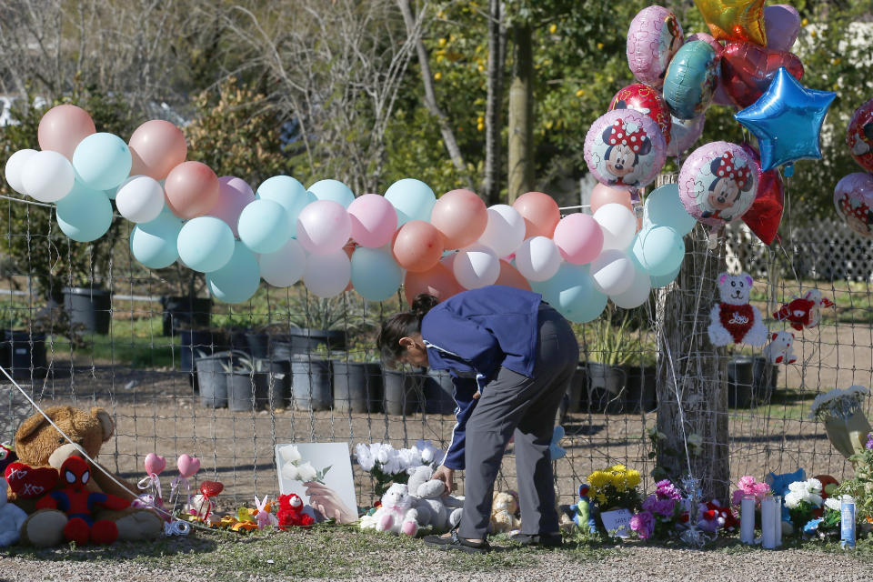 A woman places a stuffed animal at a makeshift memorial Thursday, Jan. 23, 2020, in front of the home where Rachel Henry was arrested on suspicion of killing her three children after they were found dead inside the family home earlier in the week, in Phoenix. (AP Photo/Ross D. Franklin)