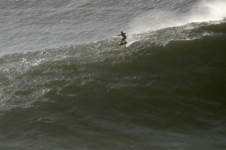 A surfer rides an hydrofoil board down a wave during a tow surfing session at Praia do Norte or North Beach in Nazare, Portugal, Thursday, Oct. 29, 2020. A big swell generated earlier in the week by Hurricane Epsilon in the North Atlantic, reached the Portuguese west coast drawing big wave surfers to Nazare. (AP Photo/Pedro Rocha)