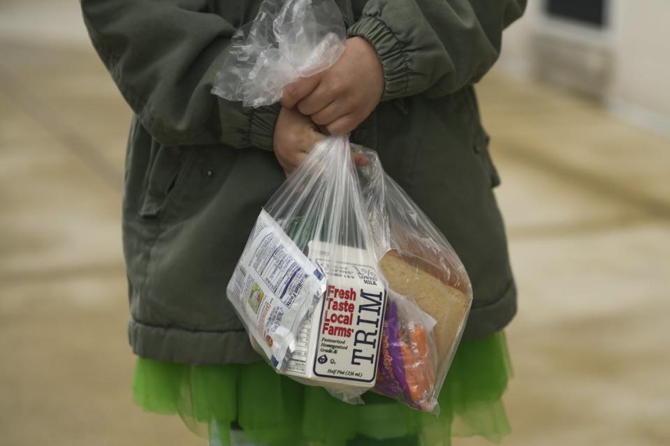 Child carries lunch in plastic bag