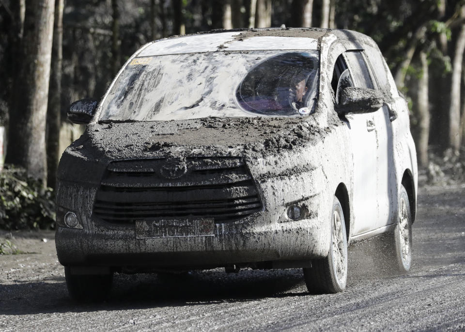 An ash-covered vehicle drives down a muddy road as Taal volcano continues to erupt in Tagaytay, Cavite province, southern Philippines on Monday, Jan. 13, 2020. Red-hot lava gushed out of a volcano near the Philippine capital on Monday, as thousands of people fled the area through heavy ash. Experts warned that the eruption could get worse and plans were being made to evacuate hundreds of thousands. (AP Photo/Aaron Favila)