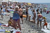 People enjoy the beach in the Black Sea resort of Sochi, Russia Sunday, July 5, 2020. Tens of thousands of vacation-goers in Russia and Ukraine have descended on Black Sea beaches, paying little attention to safety measures despite levels of contagion still remaining high in both countries. (AP Photo/Artur Lebedev)